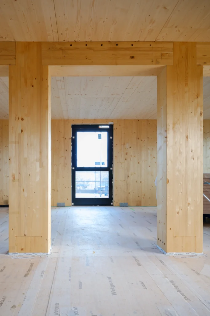 doorkijk door de houten kolommen naar een raam met balkon