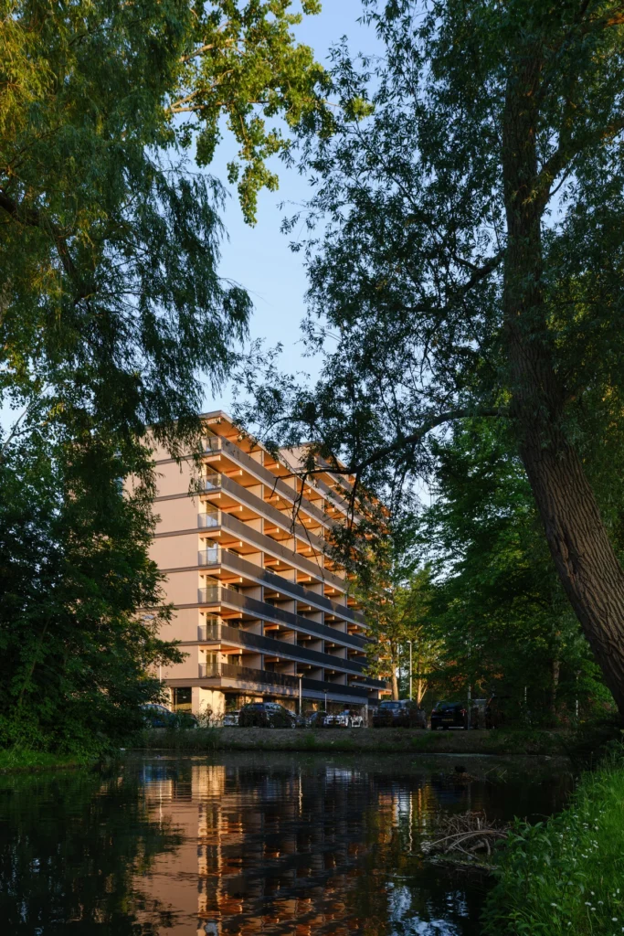 gebouw met houten balkons tussen de bomen aan het water bij zonsondergang
